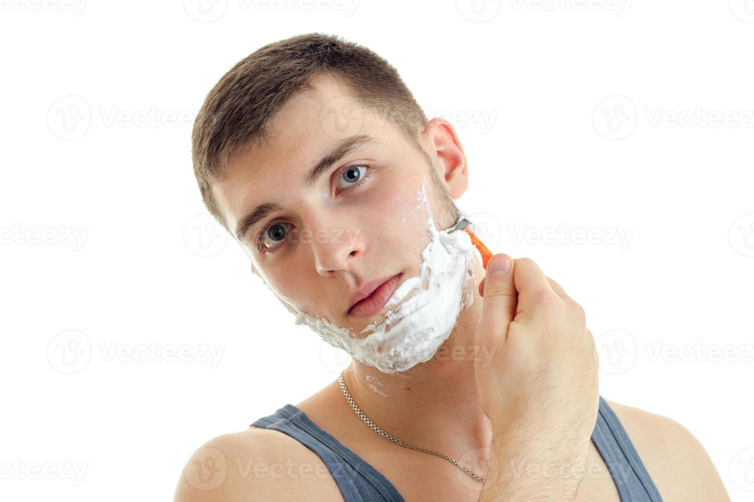 Porträt eines bemerkenswerten jungen Mannes mit Schaum im Gesicht, geneigtem Kopf und rasierter Nahaufnahme foto