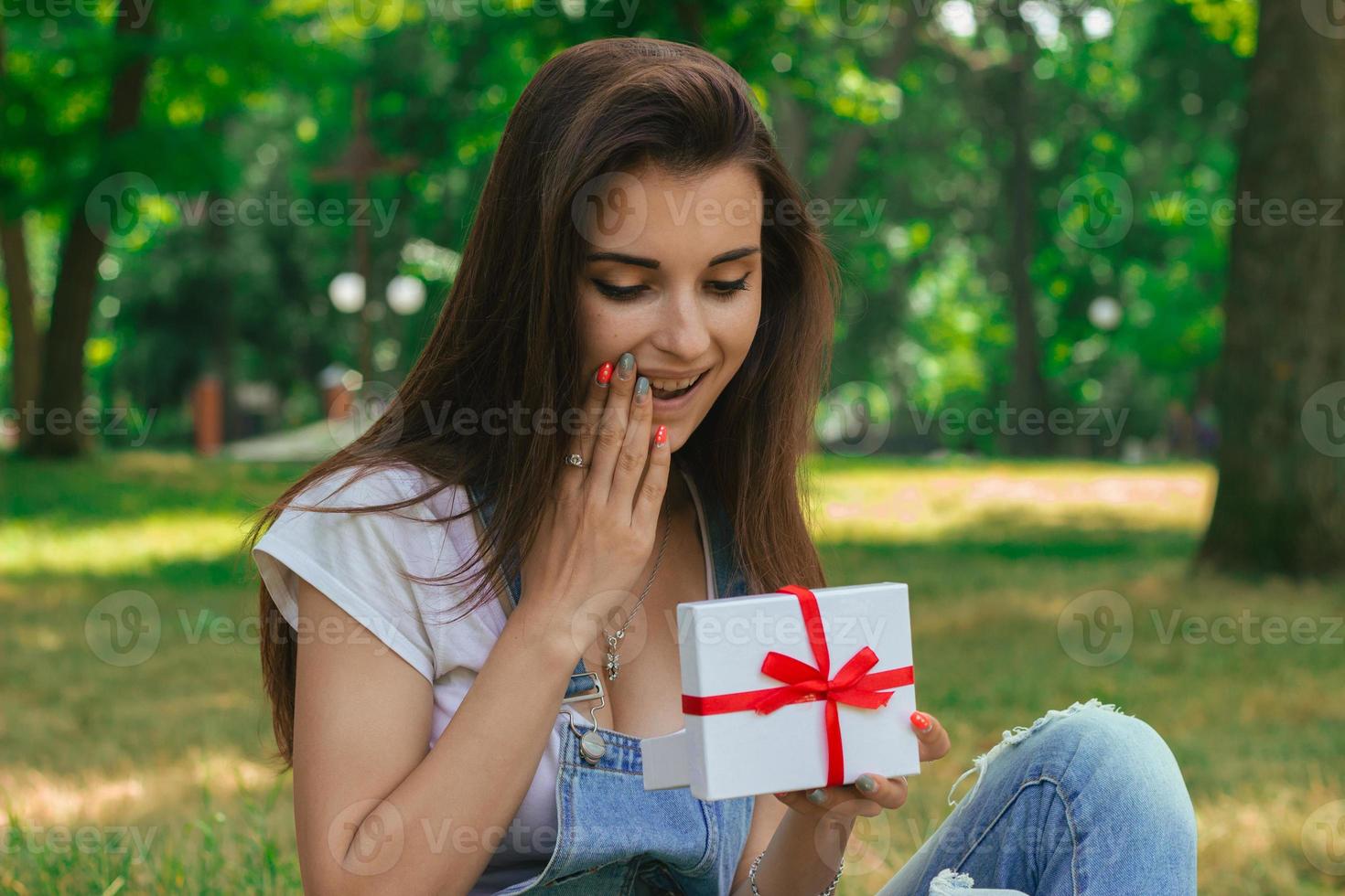 Porträt eines schönen Mädchens im Park mit einem überraschten Geschenk foto