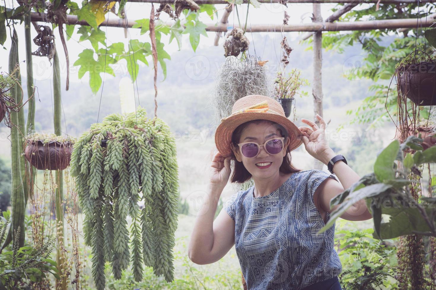 Fröhliche asiatische Frau, die vor Glück im heimischen Garten lächelt foto