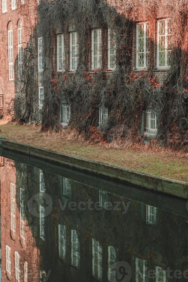 altes Gebäude mit Efeu bedeckt in der Nähe des Kanalstadtbildfotos foto