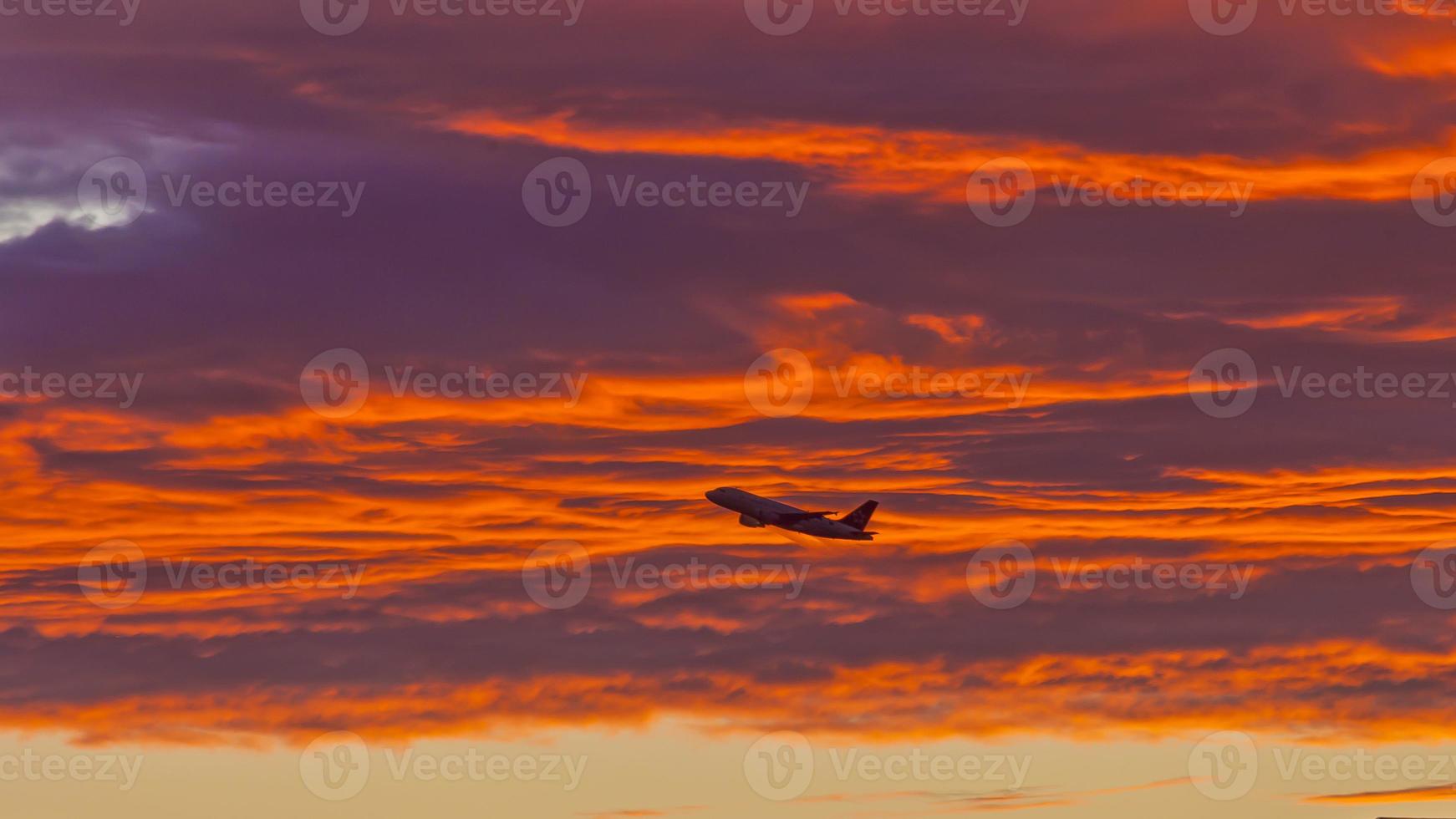 Flugzeug vor rot leuchtenden Wolken im Abendrot foto