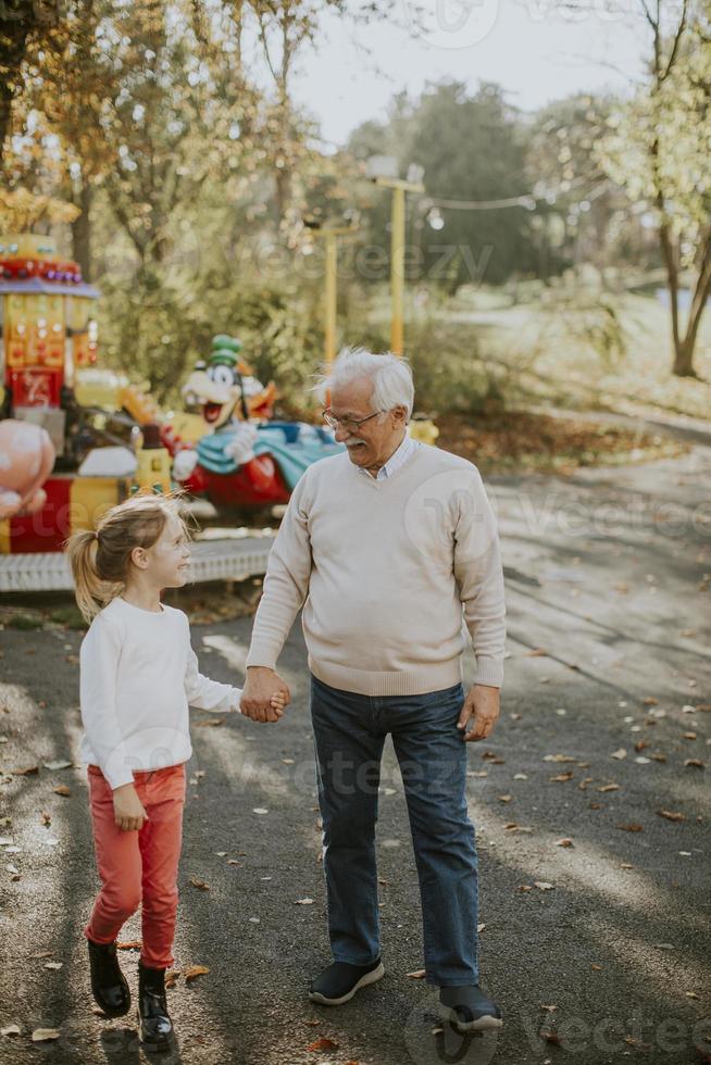 Großvater hat Spaß mit seiner kleinen Enkelin im Vergnügungspark foto