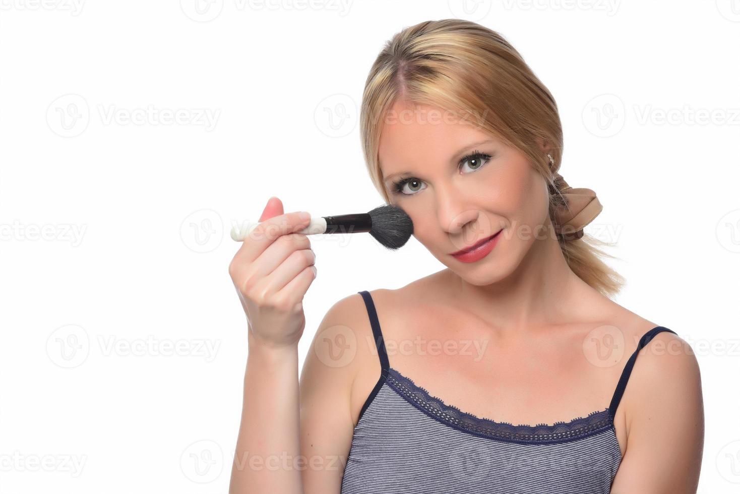 schöne junge lächelnde frau tragen make-up mit pinsel auf. isoliert foto