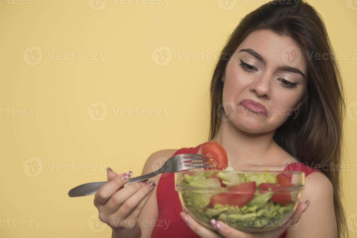 Porträt eines glücklichen, verspielten Mädchens, das frischen Salat aus einem Bogen isst foto