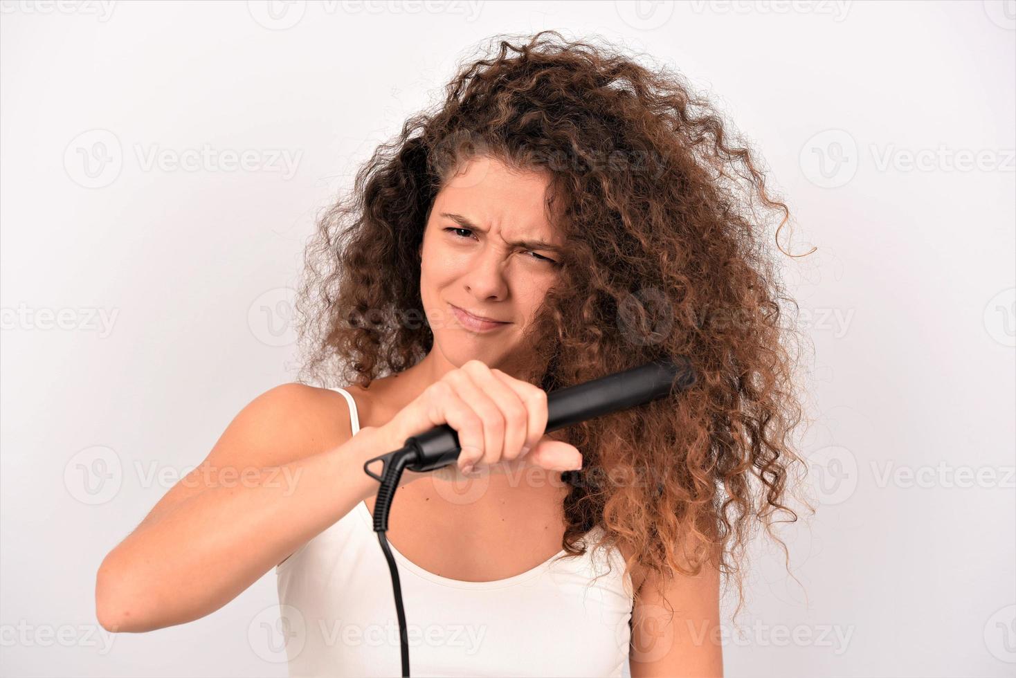 Mädchen mit welligem Haar bügelt, glättet unordentliche Locken, Keratin-Therapiebehandlung foto