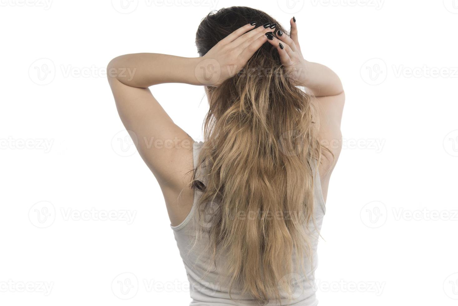 weibliches Modell, das ihr Haar anordnet. Frau, die Haare in einem Brötchen bindet. foto