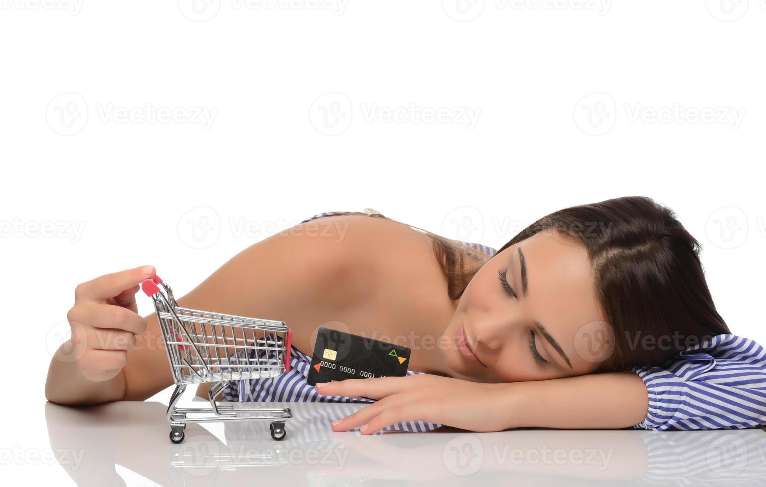 Kreditkarte in der Hand einer Frau und ein kleiner Souvenirwagen. Einkaufen, Groß- und Einzelhandel, Rabatte, Kauf auf Kredit, Bonität. foto