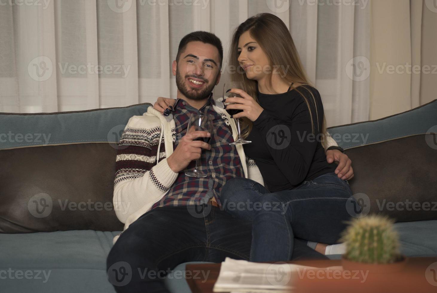 fröhliches glückliches paar, das zu hause wein trinkt. Verabredungsabend zu Hause, Weingläser klirren. foto