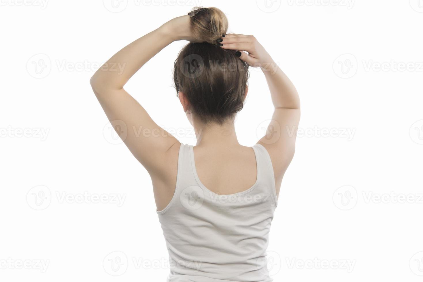 weibliches Modell, das ihr Haar anordnet. Frau, die Haare in einem Brötchen bindet. foto