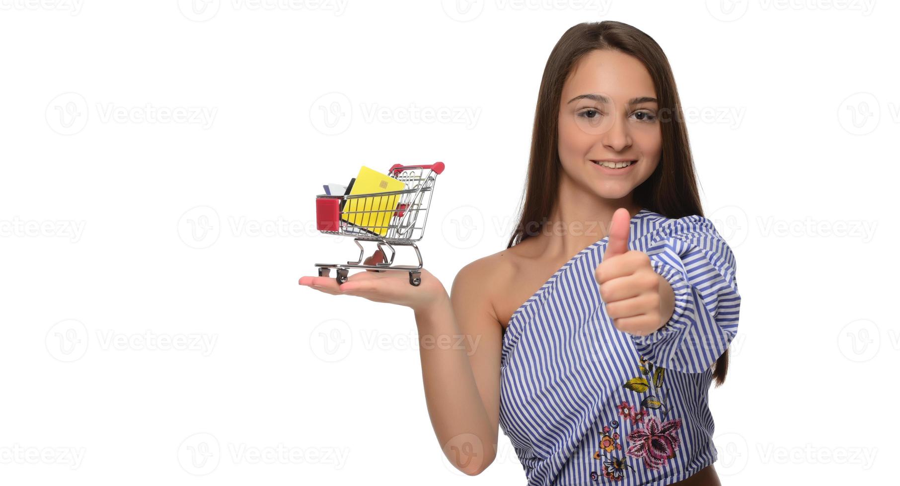 Kreditkarte in der Hand einer Frau und ein kleiner Souvenirwagen. Einkaufen, Groß- und Einzelhandel, Rabatte, Kauf auf Kredit, Bonität. foto