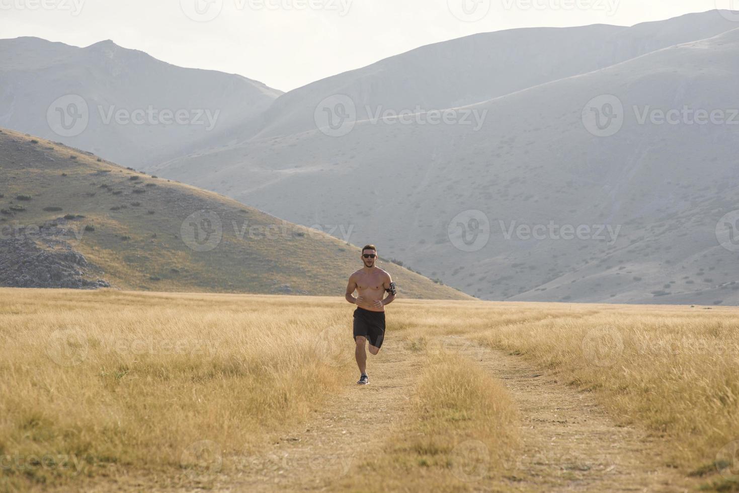 sportlicher Läufer, der im Sommer auf dem Bergplateau läuft foto