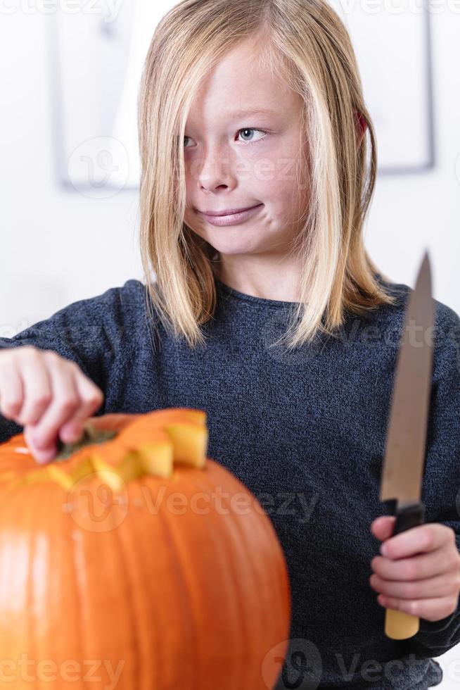 schöner blonder Junge, der Kürbis mit Messer für Halloween schnitzt. Halloween-Konzept foto