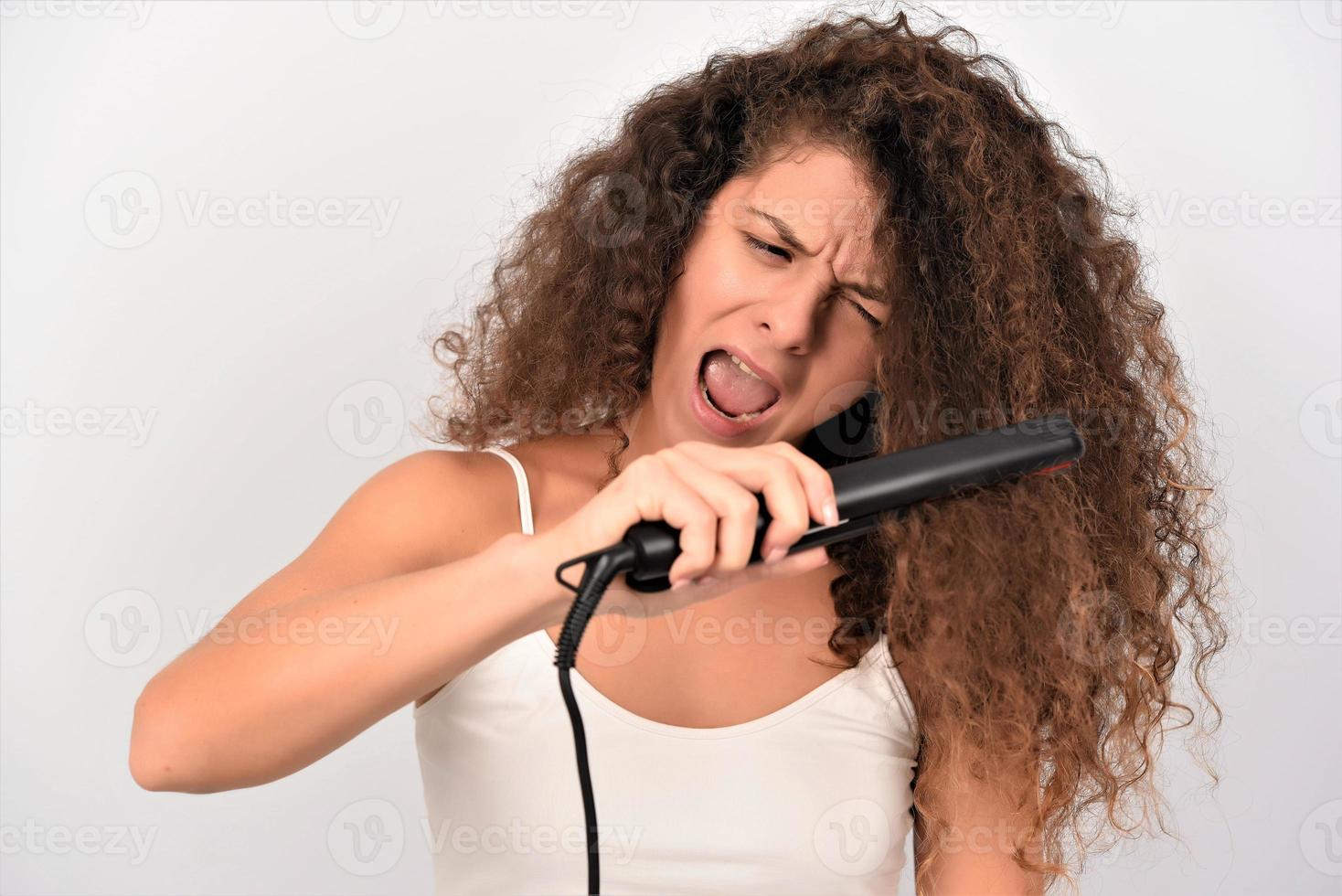 Mädchen mit welligem Haar bügelt, glättet unordentliche Locken, Keratin-Therapiebehandlung foto