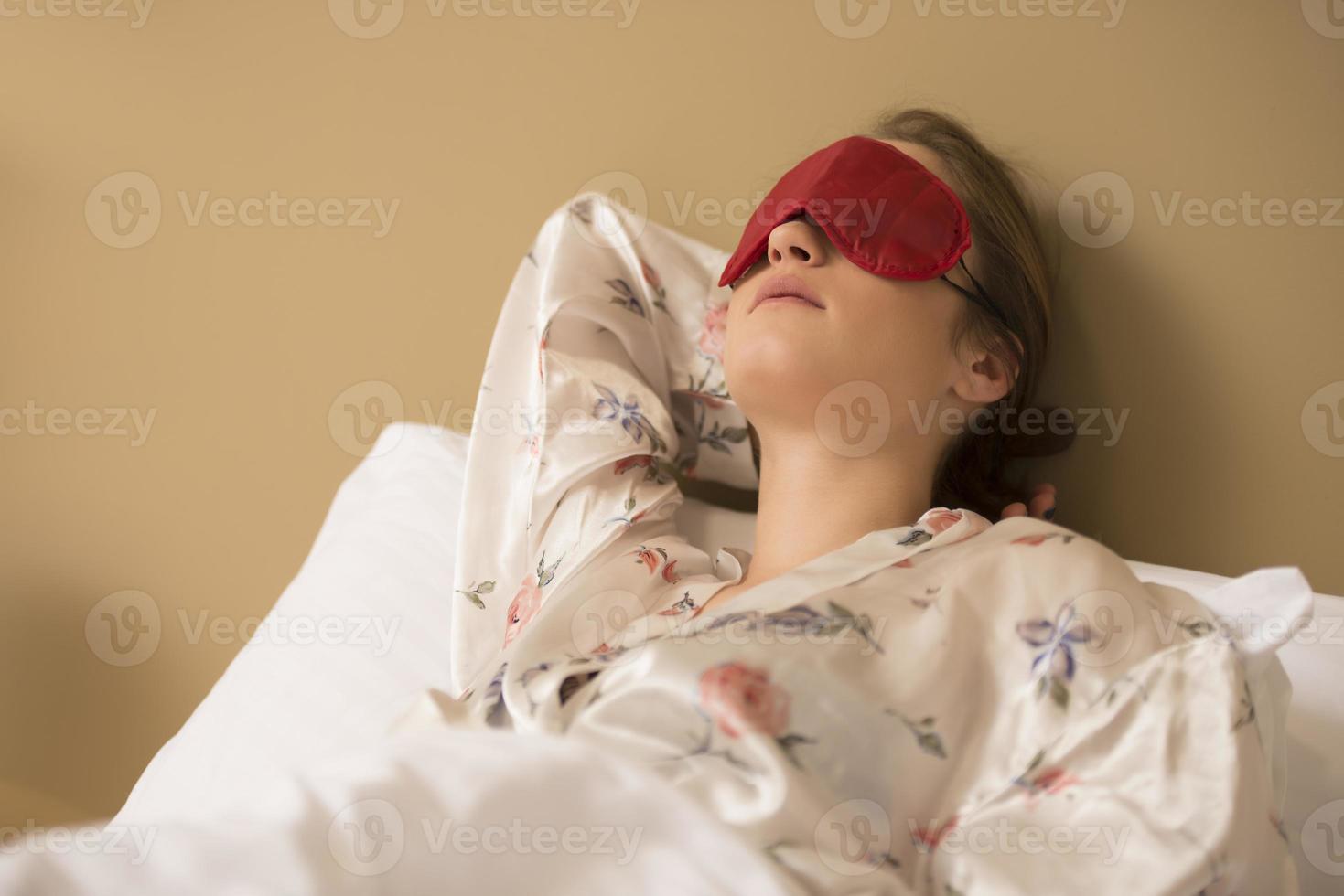 eine junge Frau, die mit einer augenbedeckenden Maske schläft. foto