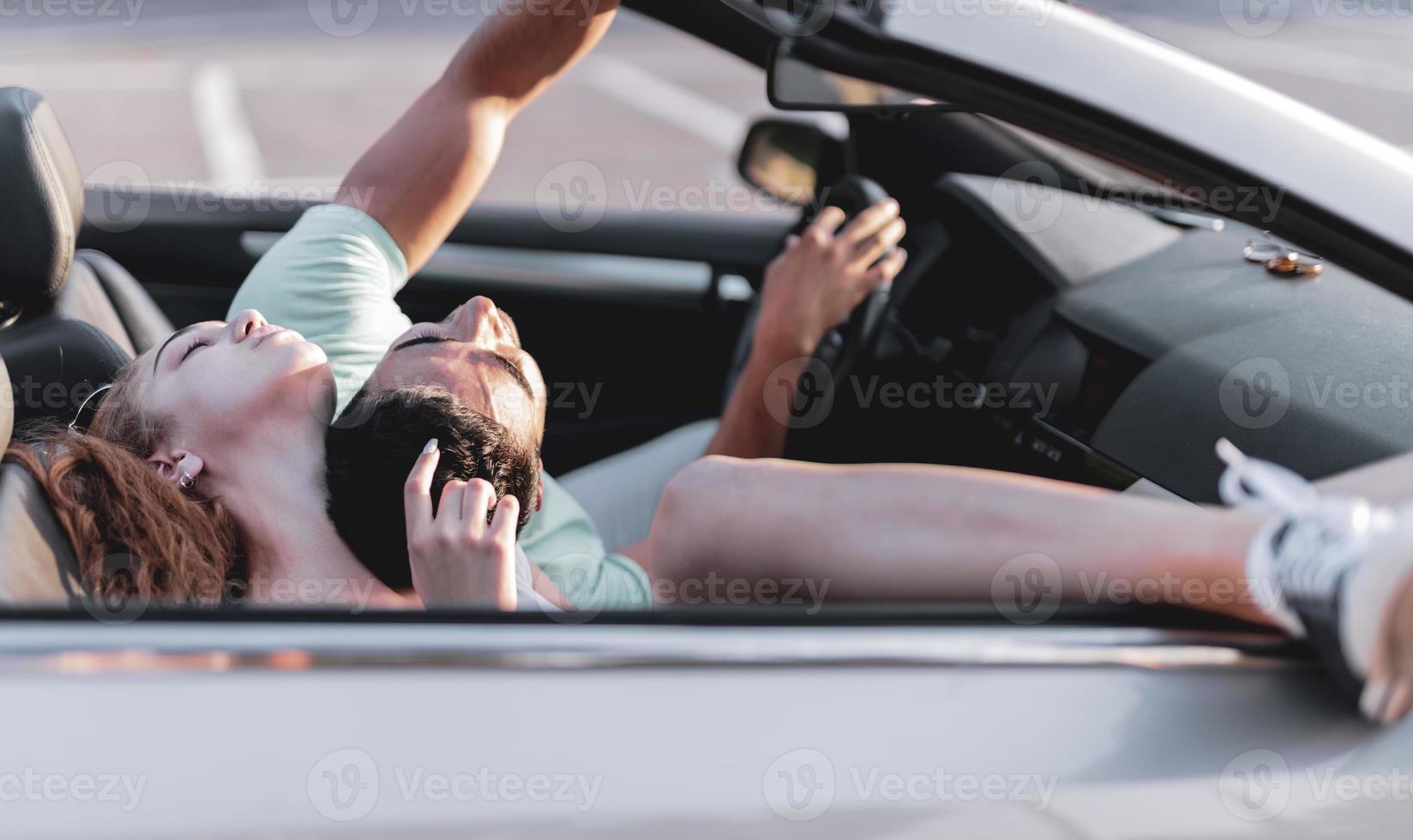 freunde, die spaß bei der autoreise um die welt haben. Verliebtes Paar mit erhobenen Armen auf einem Cabrio. foto