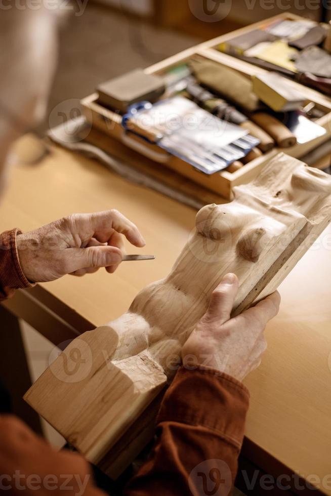 Künstler schleift Holzskulptur. Tischler, der in der Werkstatt mit Holz arbeitet. Mann und sein Hobby. Detailansicht, nur Hände im Rahmen. foto