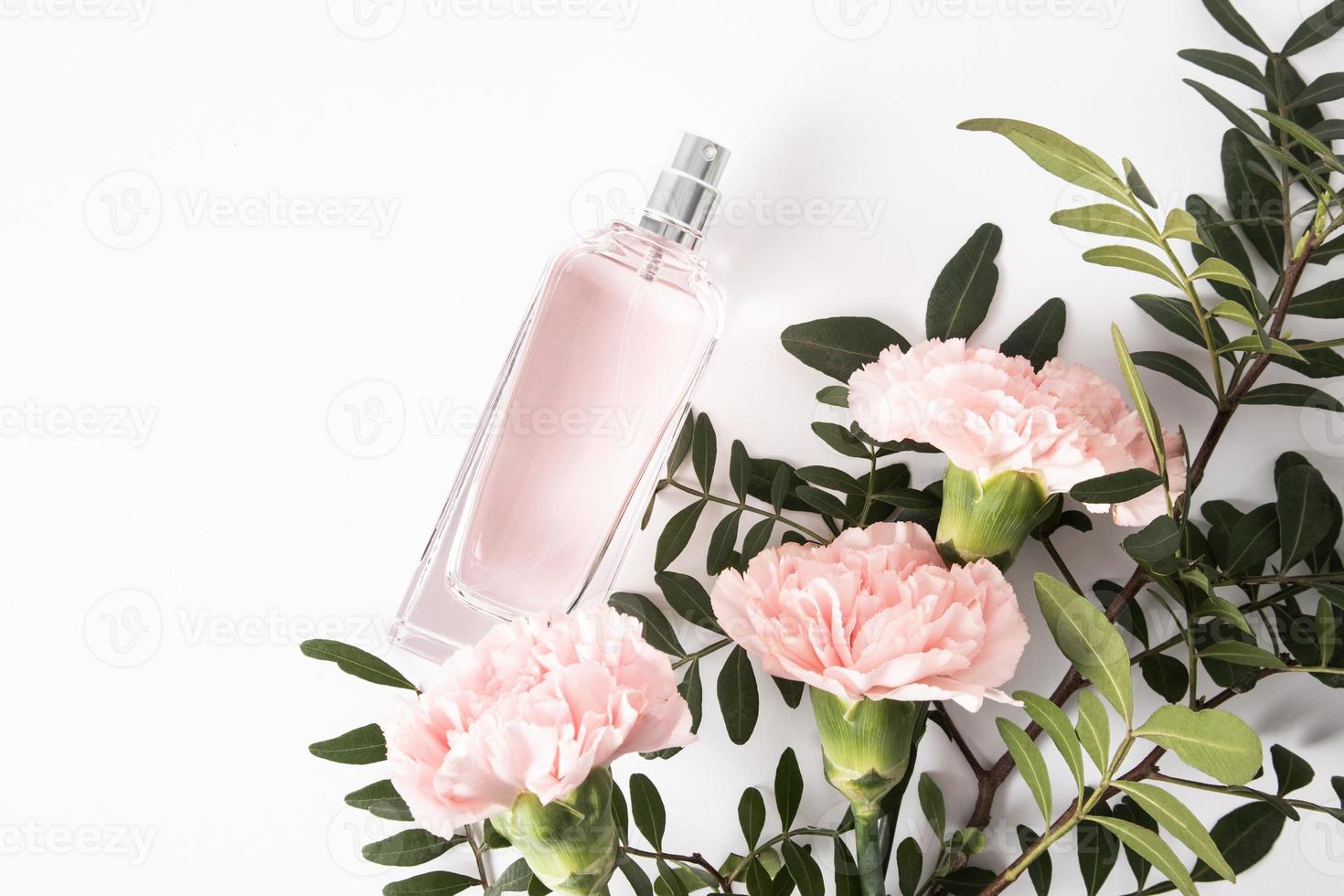 eine schicke Flasche Damenparfüm oder Eau de Parfum auf weißem Hintergrund zwischen schönen rosa Nelken und grünen Zweigen. ein Kopierraum. foto