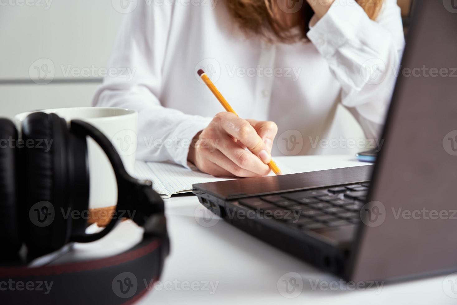 Heimarbeit. Frau macht sich Notizen im Notizbuch und benutzt Laptop zum Lernen. foto