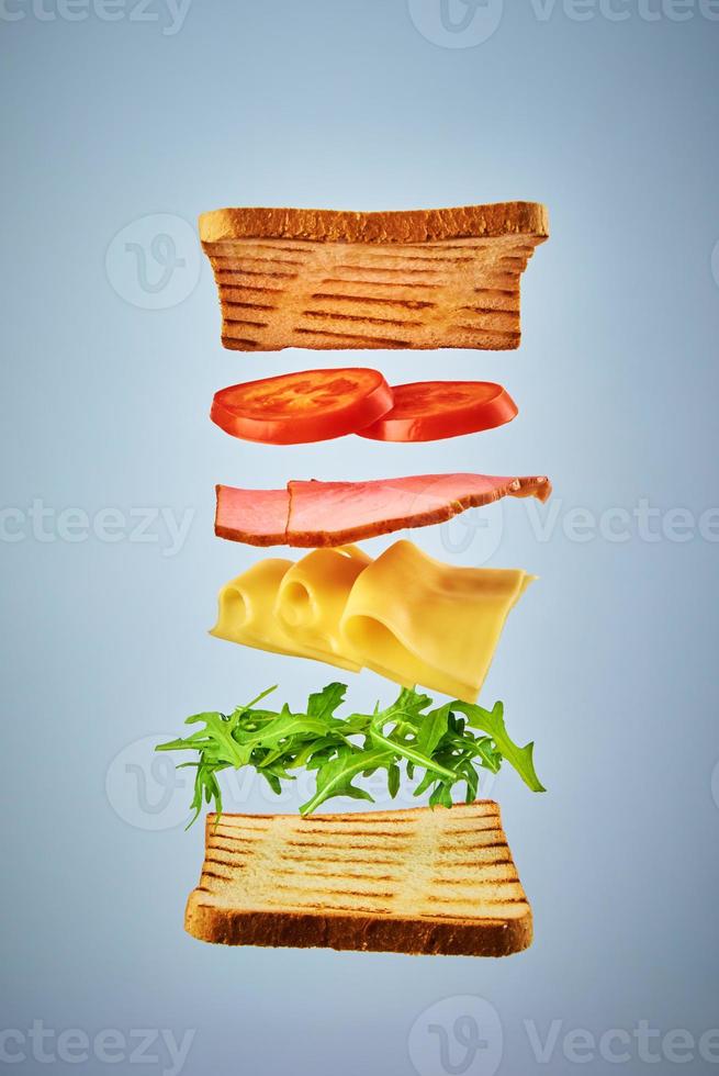 Sandwich mit fliegenden Zutaten auf blauem Hintergrund. Fly-Food-Konzept foto