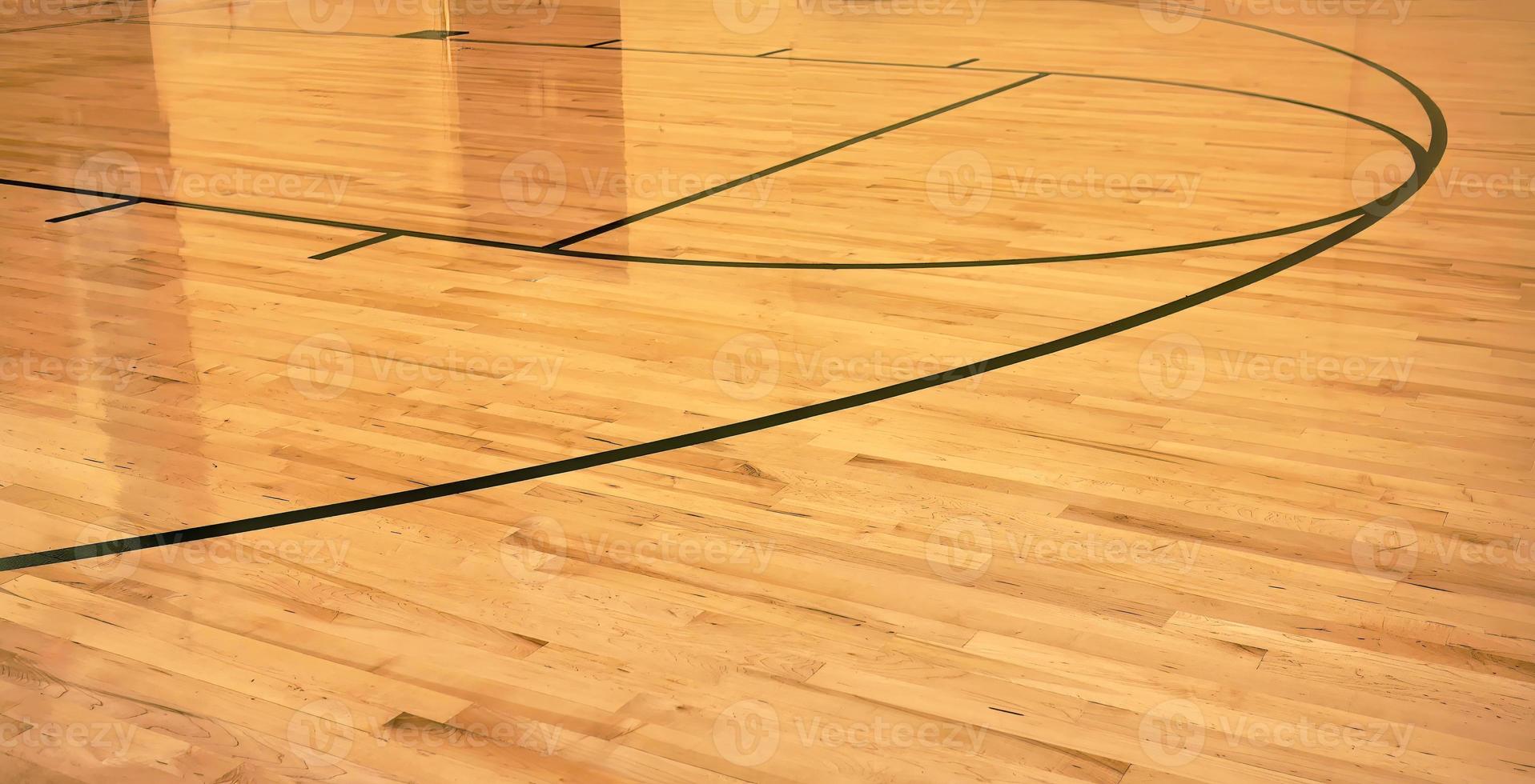 innenraum eines leeren modernen basketballhallensportplatzes, halbglänzender holzboden, künstliche lichter reflektiert foto