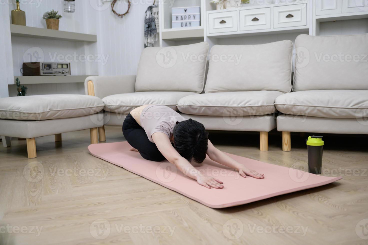 eine asiatische junge frau ist training auf fitnessmatte, übung zu hause, gesundes lebensstilkonzept foto