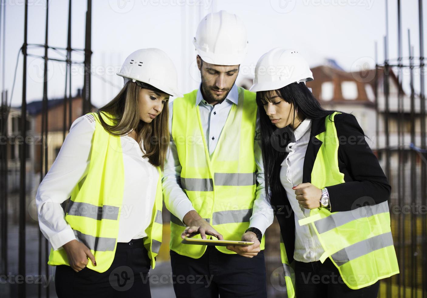 spezialisten inspizieren gewerbe-, industriebau baustelle. immobilienprojekt mit bauingenieur, investor nutzt laptop. im hintergrund kran, wolkenkratzer betonschalungen foto