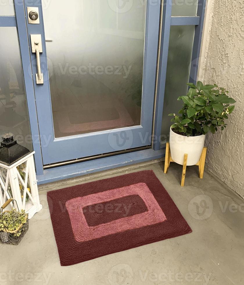 Designer-Willkommenseingangs-Fußmatte vor der Eingangstür mit Pflanze und Lampe foto