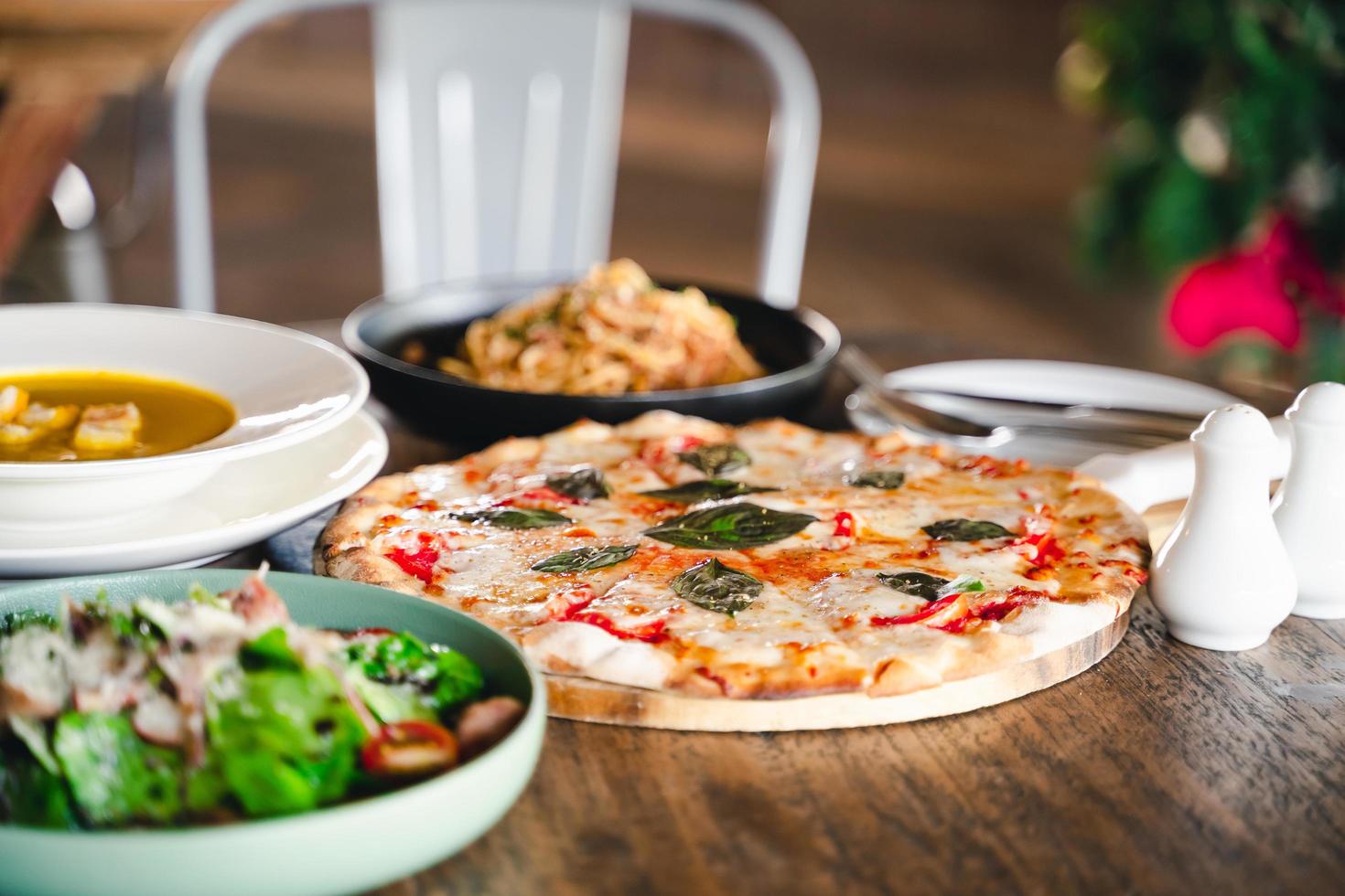 italienische speisen auf dem tisch pizza, pasta, suppe, gemüsesalat. foto