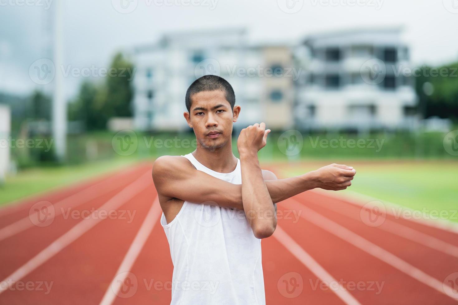 athleten sport mann läufer tragen weiße sportbekleidung zum dehnen und aufwärmen, bevor sie auf einer laufbahn in einem stadion üben. läufersportkonzept. foto