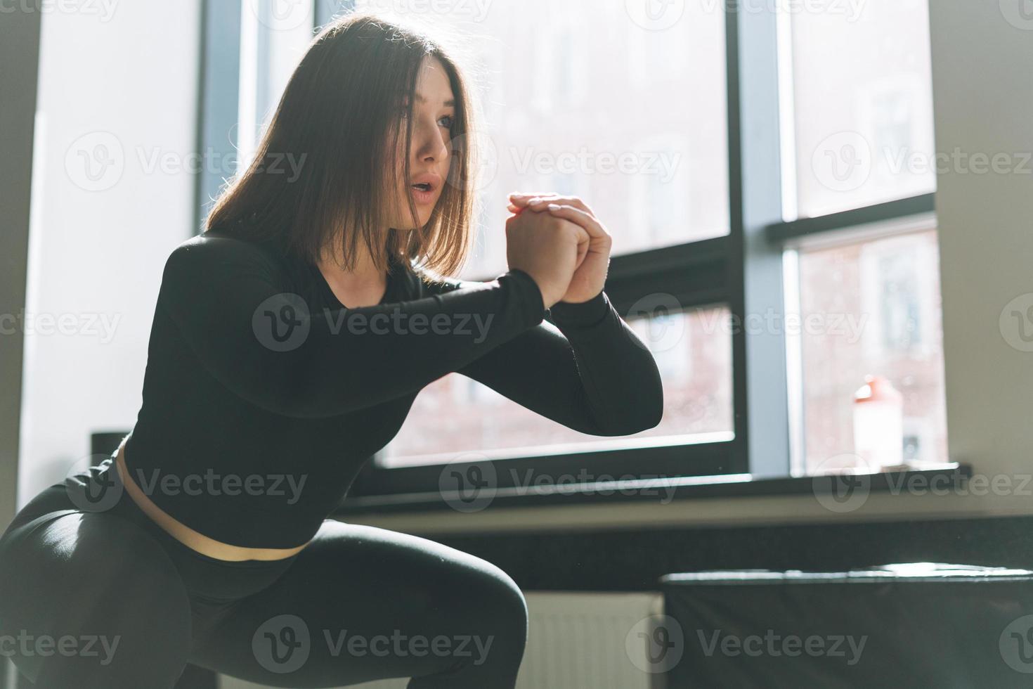 junge brünette frau trainiert ihre muskeln auf der matte im fitnessstudio des fitnessclubs foto