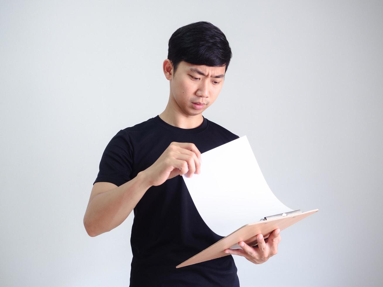 junger asiatischer mann offenes dokument auf holzzwischenablage ernstes gesicht auf weiß isoliert, arbeiterkonzept foto