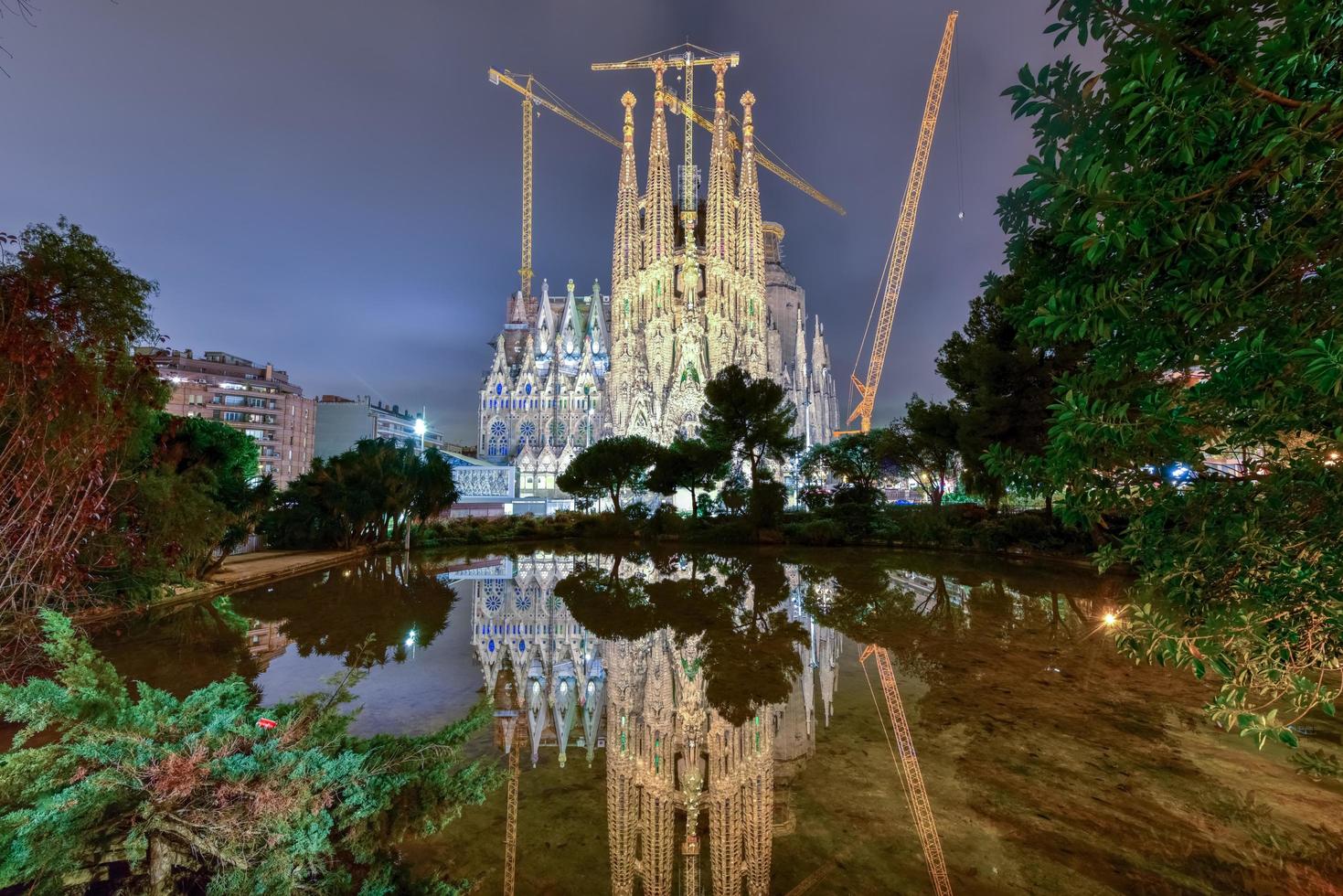 la sagrada familia nachts beleuchtet, im wasser widerspiegelnd. die kathedrale wurde von antoni gaudi entworfen und befindet sich seit 1882 im bau in barcelona, spanien, 2022 foto