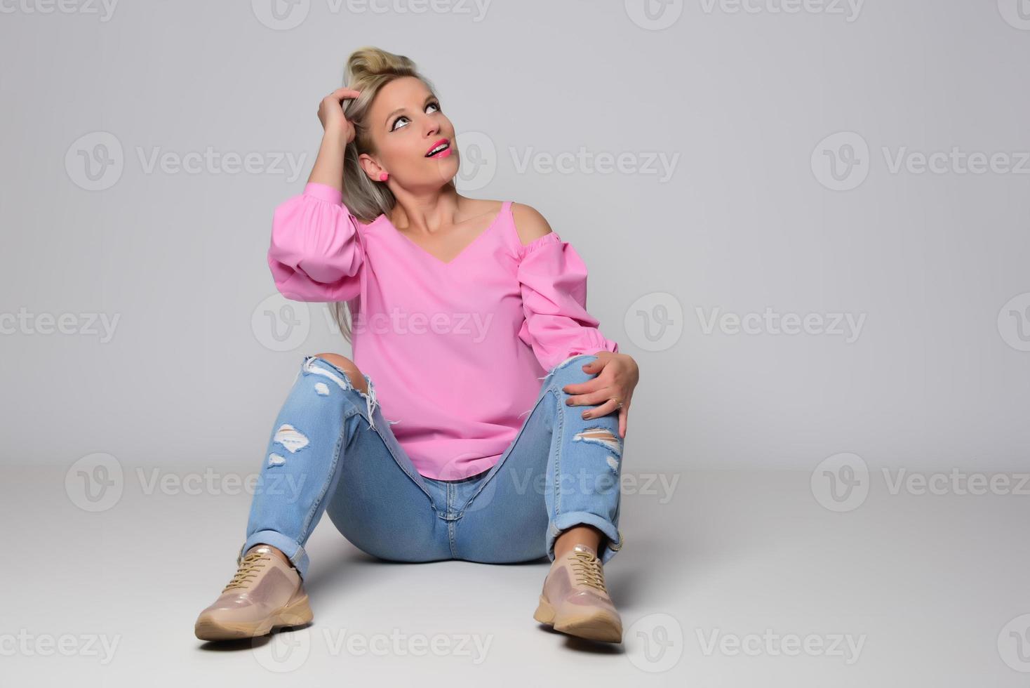 Porträt einer schönen jungen Frau in süßem rosa Hemd und blauer Jeans, die im Studio posiert. konzept von schönheit, emotionen, gesichtsausdruck, lebensstil, mode, jugendkultur foto