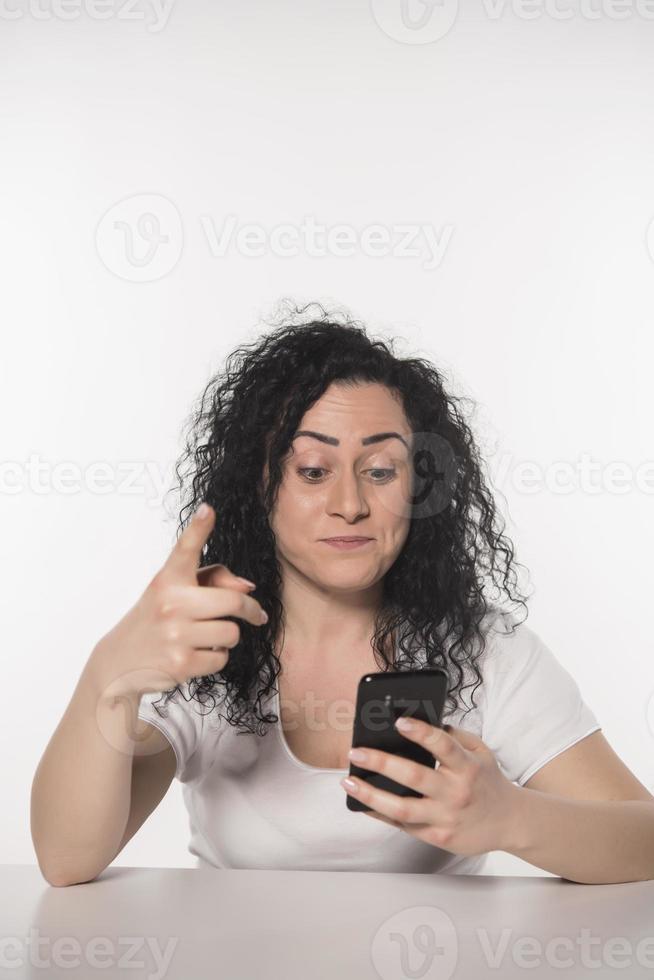 Porträt einer glücklichen Frau mit Handy gegenüber dem weißen Hintergrund isoliert foto