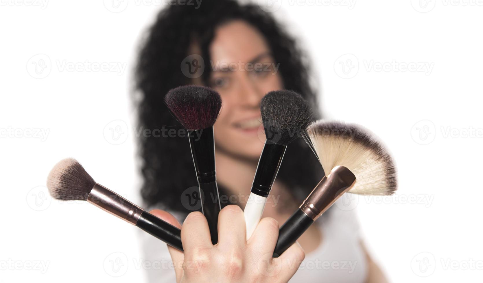 Nahaufnahmeporträt einer Frau mit Make-up-Pinsel in der Nähe des Gesichts foto