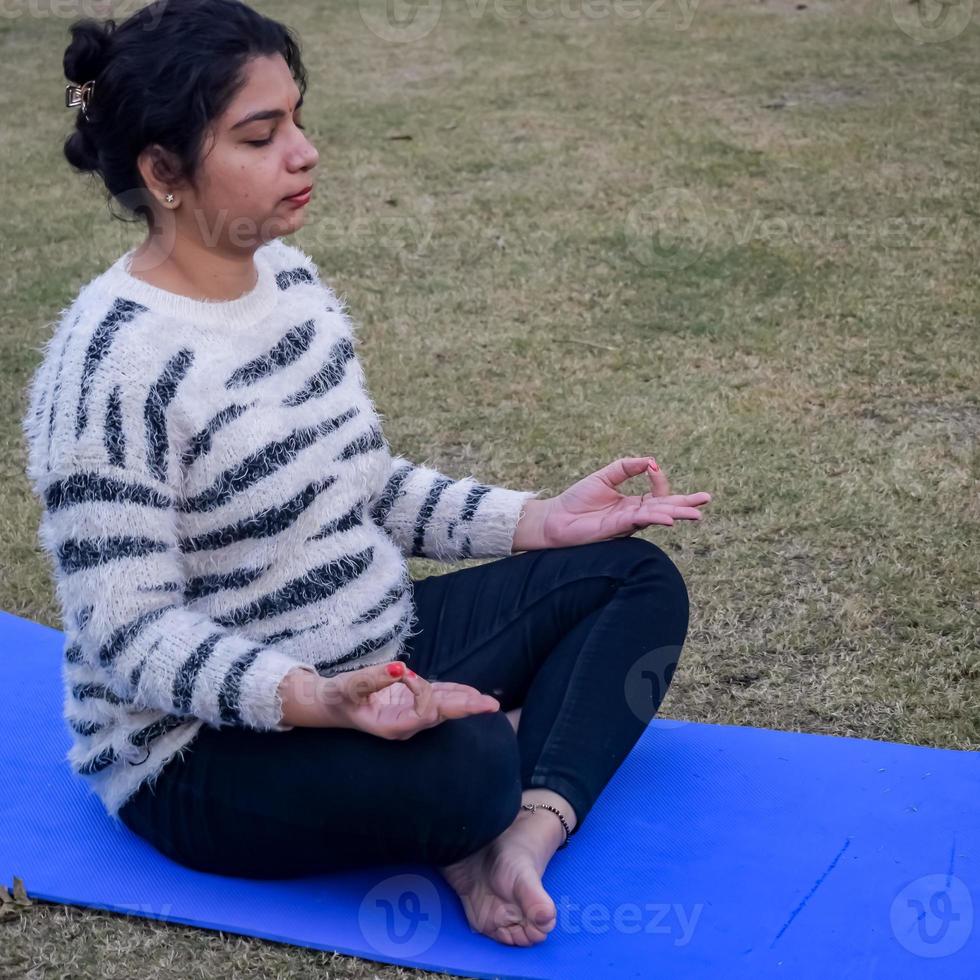 junge indische Frau, die Yoga im Freien in einem Park praktiziert. schönes Mädchen üben grundlegende Yoga-Pose. Ruhe und Entspannung, weibliches Glück. Grundlegende Yoga-Übungen im Freien foto