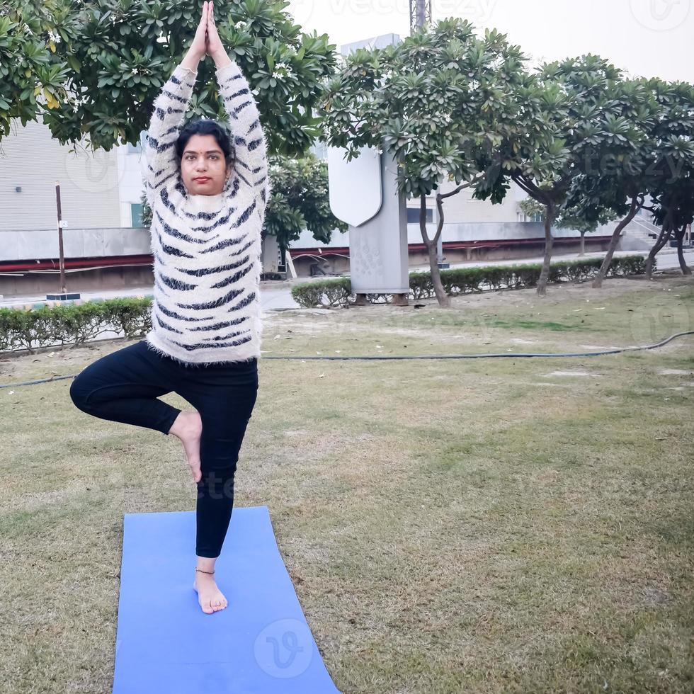 junge indische Frau, die Yoga im Freien in einem Park praktiziert. schönes Mädchen üben grundlegende Yoga-Pose. Ruhe und Entspannung, weibliches Glück. Grundlegende Yoga-Übungen im Freien foto