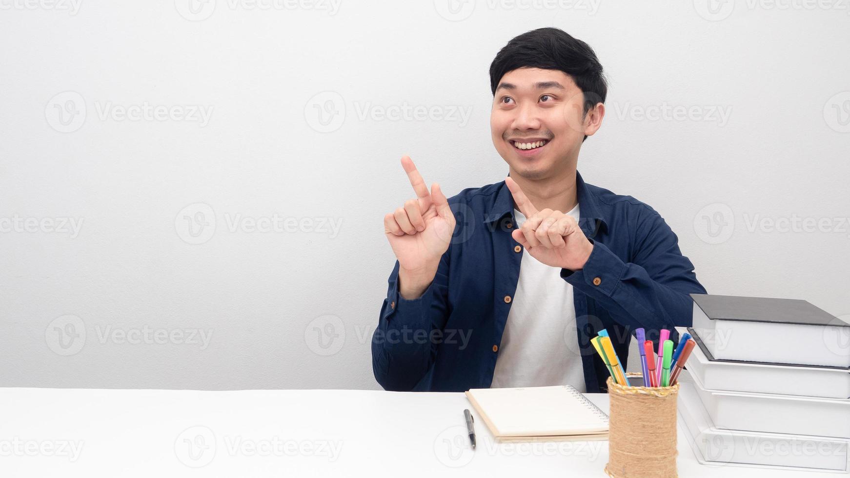 Mann sitzt lächelnd am Schreibtisch und zeigt mit dem Finger auf den Kopierbereich foto