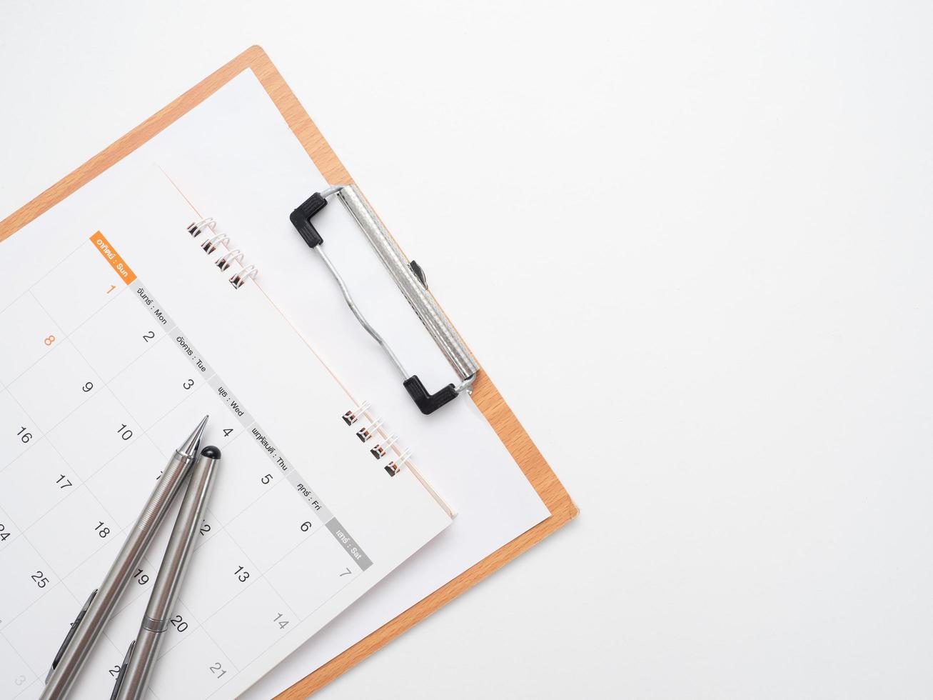 Schließen Sie herauf Stift auf Kalender mit Dokumententafel auf dem isolierten Kopienraum der Tischplattenansicht foto