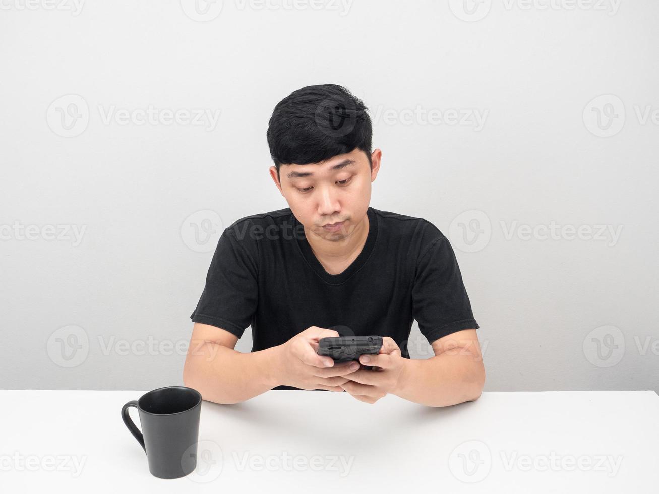 Mann mit Handy auf dem Tisch mit Kaffeetasse foto