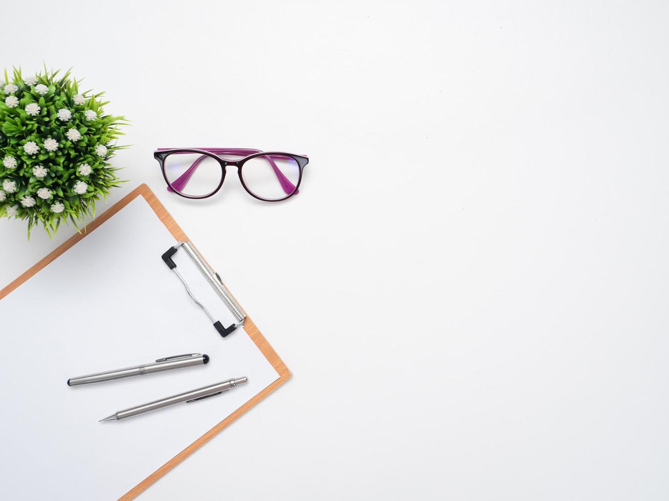 Dokumententafel mit Stift und Brille mit Vase auf dem Kopierbereich der Tischplatte foto