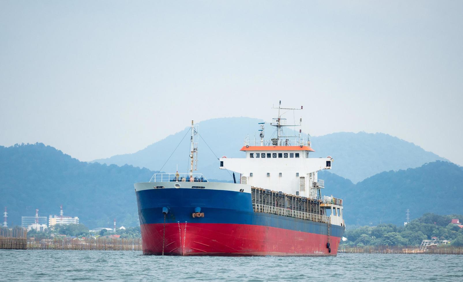 Frachtschiff im Ozean mit Insel- und Berghintergrund, Transportschiff an der Küste von Dock und Insel mit blauem Himmel foto