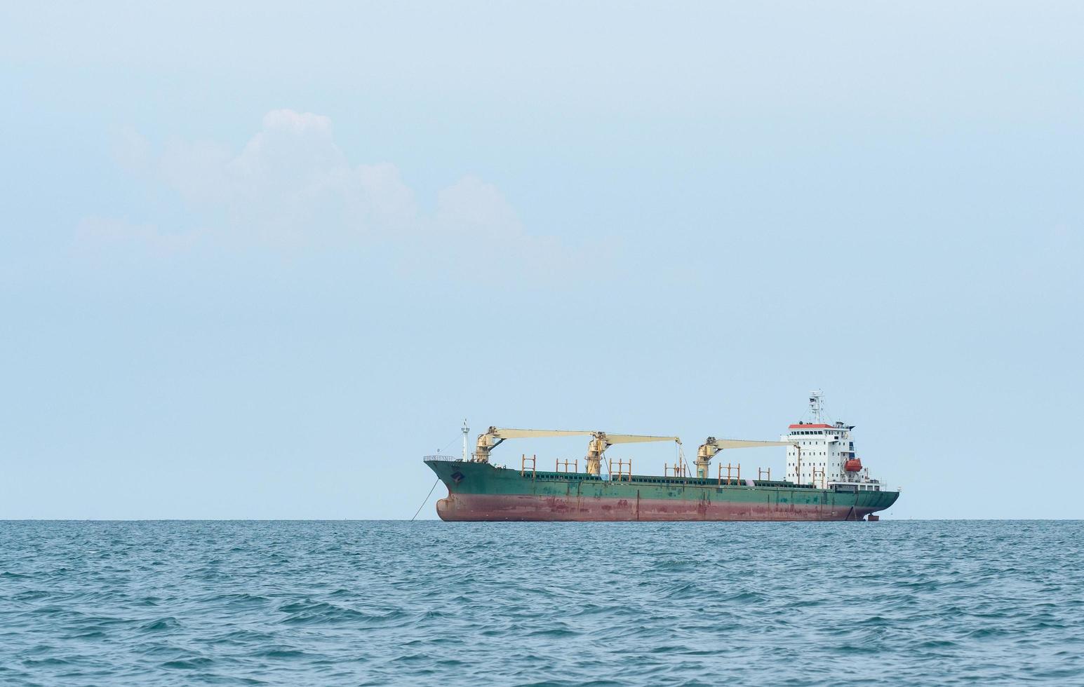 großes schiff mit kranentladung im ozean mit blauer himmellandschaft, frachtschiffkonzept im industriellen meer foto