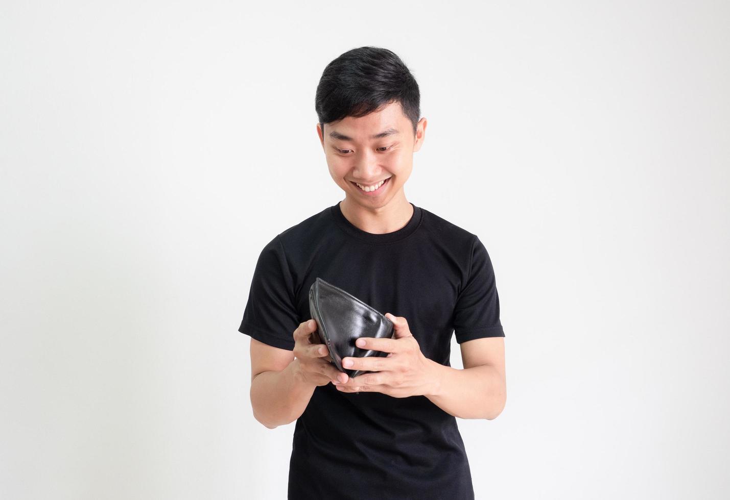 junger asiatischer mann schwarzes hemd schaut sich bargeld in seiner brieftasche mit einem lächeln an und fühlt sich glücklich und auf weiß isoliert, reiches mannkonzept foto