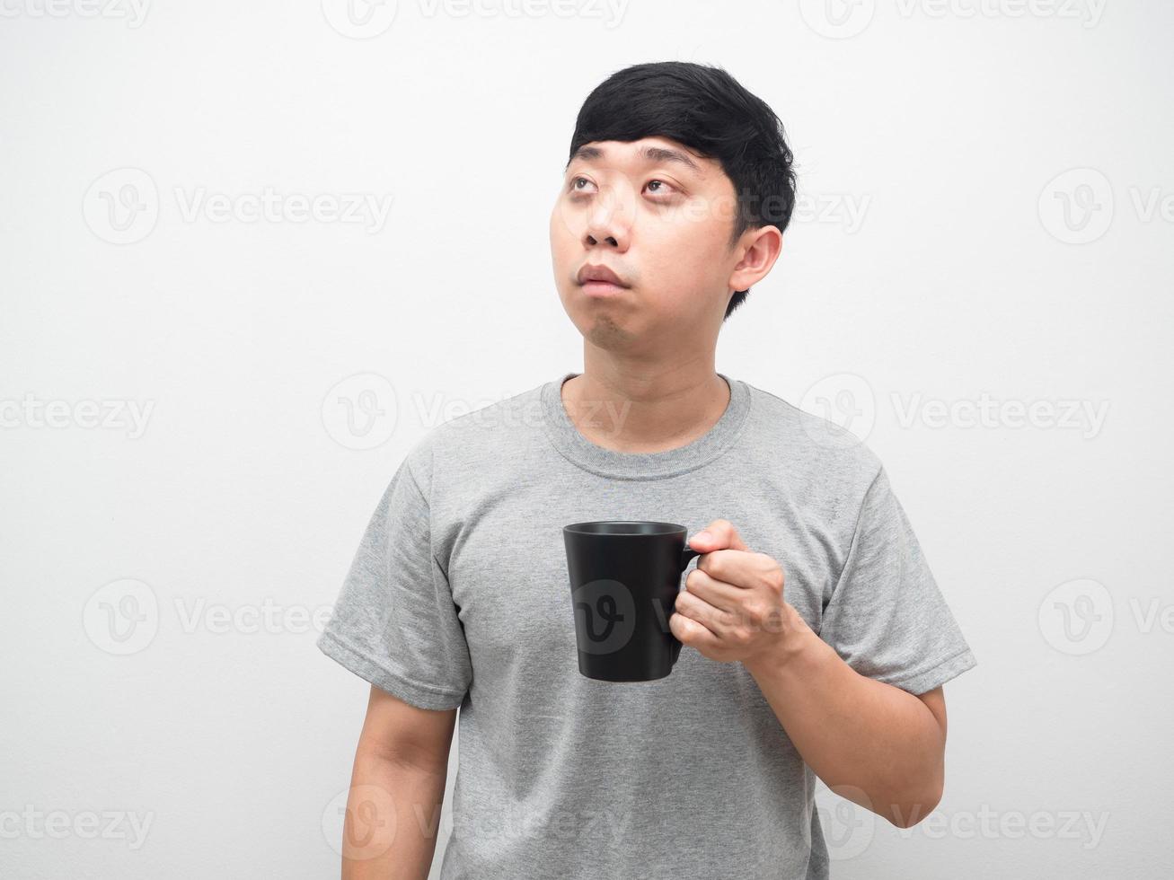 schlafloser mann, der eine kaffeetasse hält und nach oben schaut, der mann wacht morgens auf und fühlt sich schläfrig foto