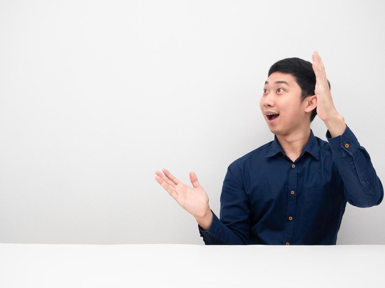 asiatischer mann, der sich erstaunt fühlt, zeigt die hand nach oben und betrachtet den weißen hintergrund des kopienraums foto