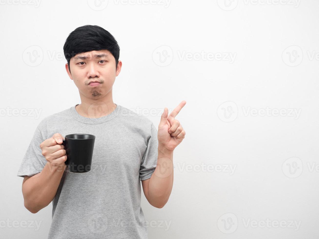 asiatischer mann, der kaffeetasse hält, zeigt mit dem finger auf den kopienraum foto