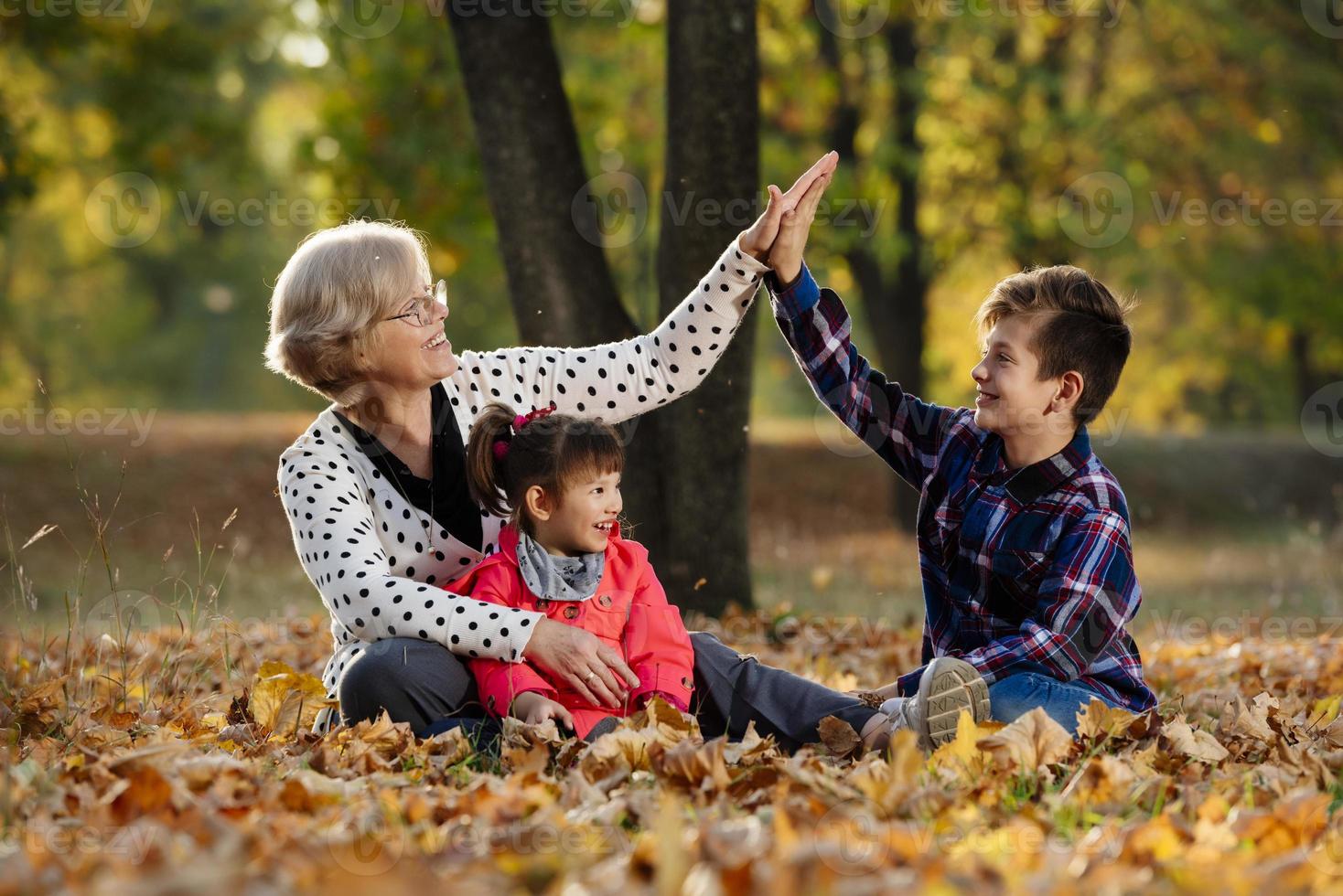 glückliche großmutter, enkelin und enkel, die im park spielen foto