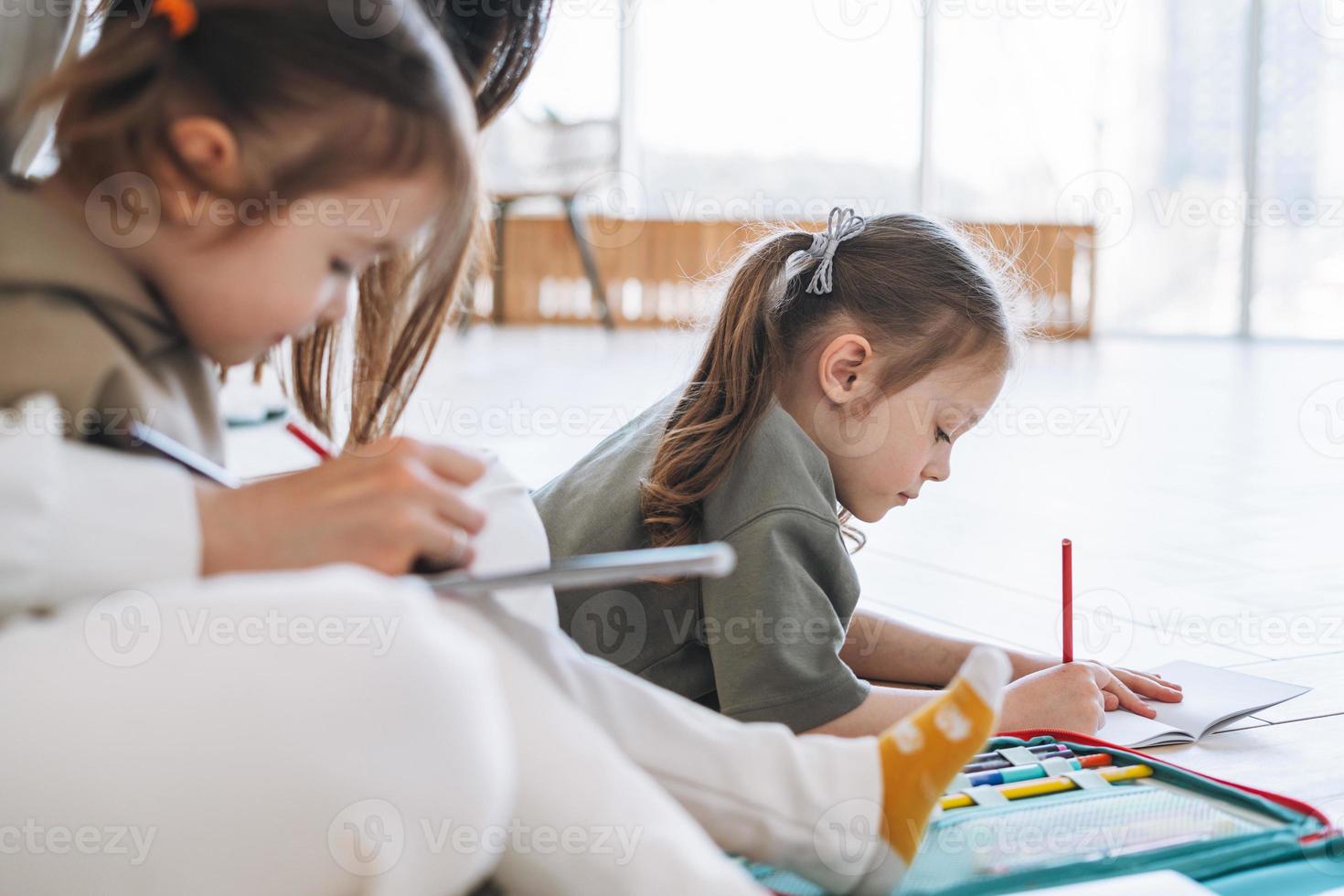 kleine mädchenschwestern im vorschulalter mit mutterzeichnung auf dem boden im hellen raum zu hause foto