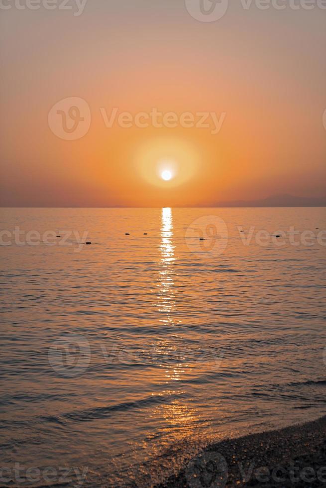 Malerischer Blick auf das Meer mit Sonne, die bei Sonnenuntergang am klaren Himmel scheint foto